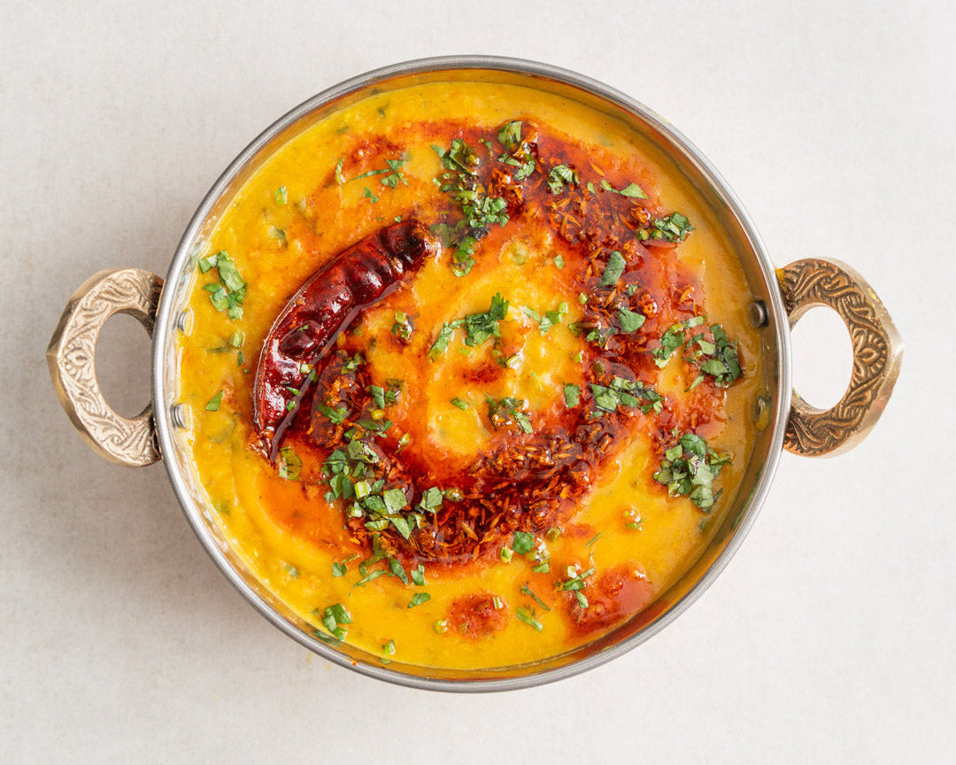 Yellow curry dish with garnishes in a decorative bowl on a light background